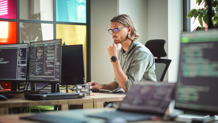 Focused Caucasian Man Coding On Desktop Computer in Stylish Office Space. Male Software Engineer...