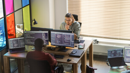 Diverse Colleagues Writing Code on Desktop Computers With Professional Multiple Monitors Setup....
