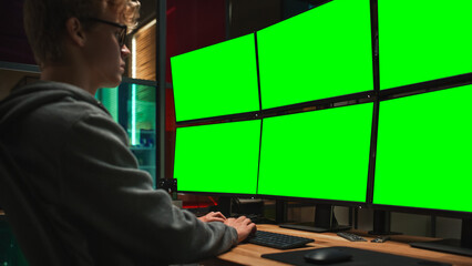 Young Caucasian Man Writing Code on Professional Six Monitors Setup With Green Screen Chromakey....