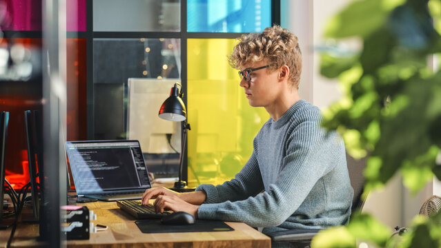 Side View of Male Data Science Intern Writing Lines Of Code on Desktop Computer In Stylish Office. Young Caucasian Man Solving Software Problems for Big Tech Company. Fututre Programmer Learns Coding. - Powered by Adobe