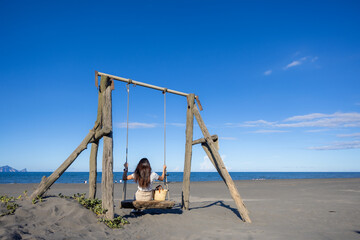 Woman play with swing on sand beach