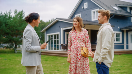 Young Couple Viewing Property for Sale, Talking with Professional Real Estate Agent Outside the...