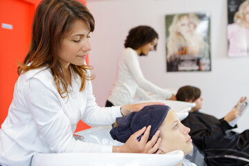 Obraz na płótnie Canvas hairdresser woman washes hair head to client in the chair