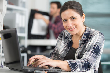 happy female technician using laptop to analyse server
