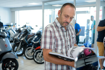 Naklejka na ściany i meble man choosing new motorbike in the store