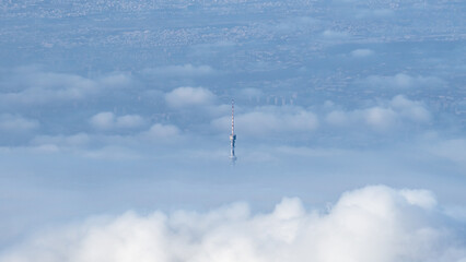 a TV tower in the clouds. clouds over the city. foggy city