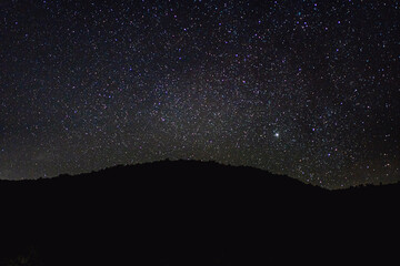 Night sky with stars and hill in the foreground. Astronomical abstract background