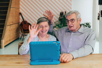 senior couple at home in remote video call conversation with family and friends using pad