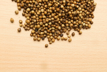 Pile of roasted coriander seeds isolated on brown wooden background