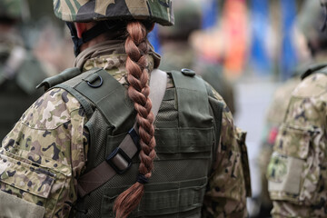 Women in armed forces. Close up view of the braided hair of a young woman soldier part of the army.