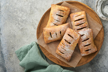 Hand pies. Mini puff pastry or hand pies stuffed with apple and sprinkle sugar powder in wooden plate. Homemade pie snack with crust for breakfast rustic photo.  Copy space.