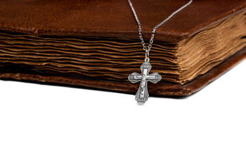 isolated on a white background jewelry silver cross on a chain with a shadow lies on an old book