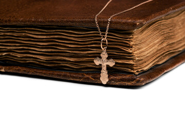 isolated on a white background jewelry golden cross on a chain with a shadow lies on an old book