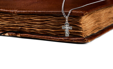 isolated on a white background jewelry silver cross on a chain with a shadow lies on an old book