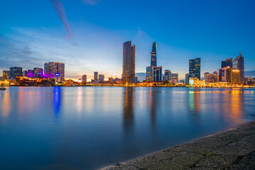 Fototapeta premium Ho Chi Minh City skyline and the Saigon River at night. Amazing colorful view of skyscraper and other modern buildings. Travel concept