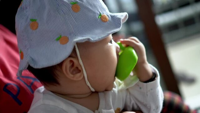 Close up chinese boy wear hat and chew teether