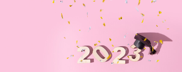 Class of 2023 concept. Numbers 2023 with black graduated cap on colored background