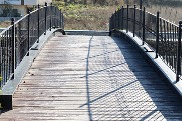 Convex and iron railings of wooden paved footbridge reinforced with steel beams