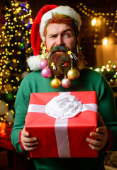 Santa man with decorated beard for New Year. Bearded male with Christmas gift. New year present box.