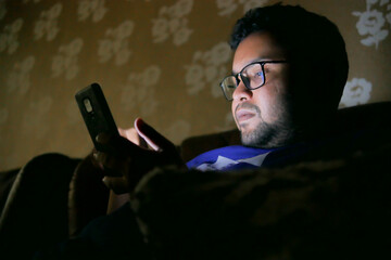  young men sitting on sofa using smart phone at night 