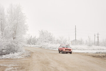 Obraz na płótnie Canvas The car is driving along a snow-covered village road
