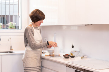Fototapeta na wymiar Catalan woman cooks healthy food in the kitchen at home in the city