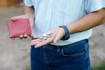 Closeup hand holds Thai baht coins and empty wallet. Concept, no money, economic crisis. Financial...