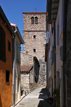 Narrow alley with residential houses and medieval church tower of Notre-Dame-de-l&lsquo;Assomption in the old town of Quillan, Occitanie region in France