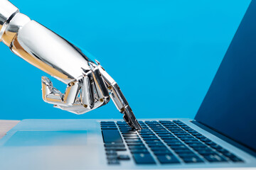 Robot hand typing on laptop