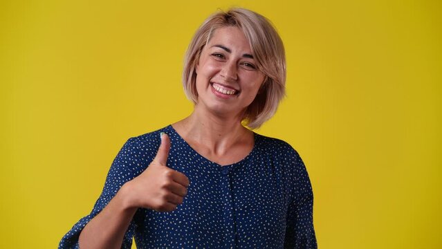 4k slow motion video of one woman thowing thumb up over yellow background.