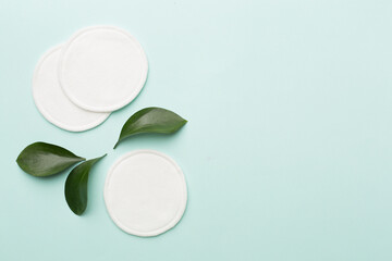 Cotton reusable pads with leaves on color background. Top view. © Liami