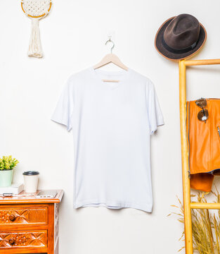 A v neck shirt hanged on the hook at the wall with minimalist decoration