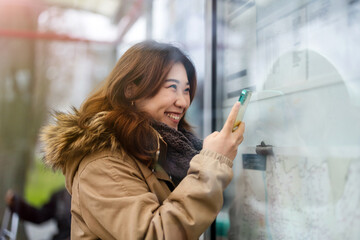 Young woman using mobile phone while standing at bus stop
