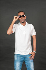 Fototapeta premium An african man with blank white polo shirt doing on the black background
