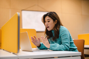 Female student working on laptop in a library cubicle
