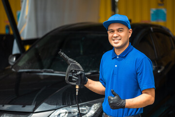 Man worker washing car service. Car wash cleaning station high pressure water. Employees clean a vehicle professionally.