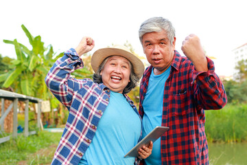 Asian elderly farmer holding a tablet Used to control the solar panel. to use electricity in agriculture. Solar system. concept of using modern agricultural technology