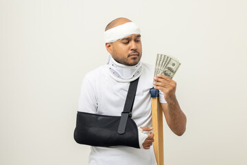 Depressed man suffering from pain counting dollar banknote payment No money to pay for medical care. Broken arm. Man put on plaster cast splint. Patient wearing sling support arm. life insurance