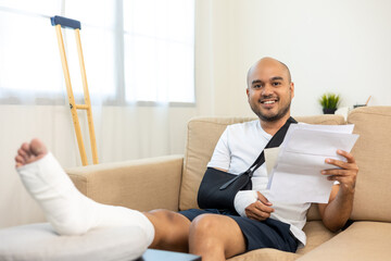 Happy man pay invoice medical expenses from accident fracture broken bone injury with leg splints in cast neck splints collar sling support arm. Social security and health concept. - obrazy, fototapety, plakaty