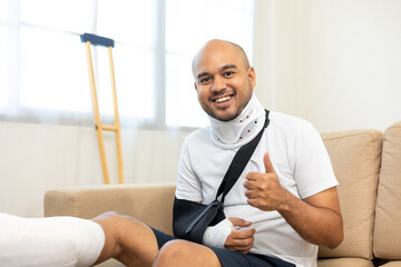 Happy man recovery from accident fracture broken bone injury with leg splints in cast neck splints...
