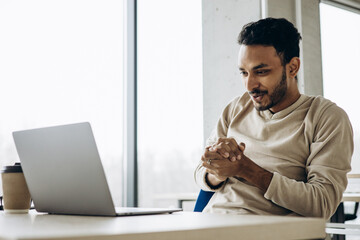 Indian business man sitting in office working on a laptop