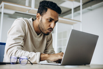 Indian business man sitting in office working on a laptop