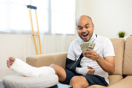 Happy Man Pay Money Medical Expenses From Accident Fracture Broken Bone Injury With Leg Splints In Cast Neck Splints Collar Sling Support Arm. Social Security And Health Insurance Concept.