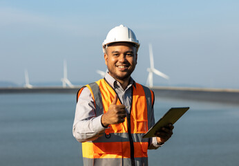 Engineer India man working with tablet at windmill farm hydroelectric Generating electricity clean...