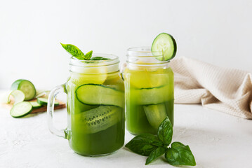 Cucumber lemonade with basil and lemon in a glass mug on table.