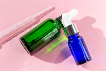 Cosmetic bottles and pipette on pink background