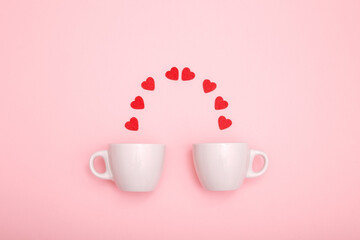 Two coffee cups and red wooden hearts on a pink background. The concept of Valentine's day, love, dating and wedding. Symbol of a romantic gift or marriage proposal. minimalism.