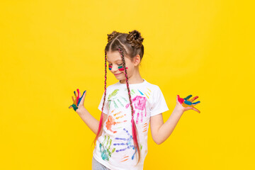 The child is playing with colorful paints. A little girl stained with paint for drawing on a yellow isolated background. Art courses for schoolchildren. Creative education of children.