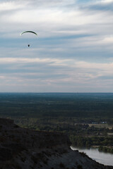 Paraglider flying in the distance above landscape.