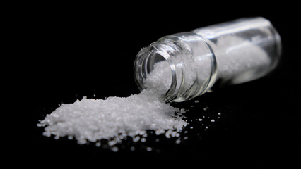 Salero abierto con sal cayendo en un fondo negro visto de cerca